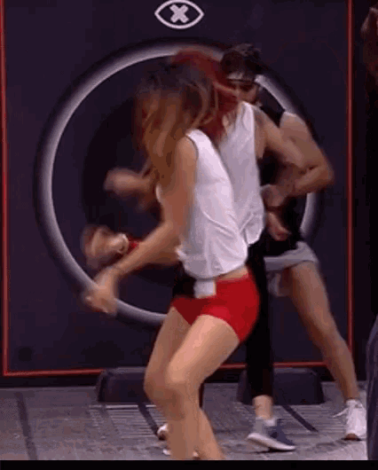 a woman in red shorts is dancing with a man in a black tank top