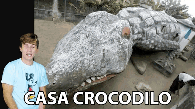 a man in a mickey mouse shirt stands in front of a large crocodile statue and the words casa crocodilo