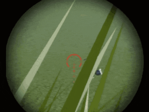a person in a sniper scope with a red circle in the middle
