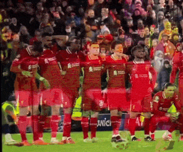 a group of soccer players are standing on a field and one of their shirts says standard chartered bank
