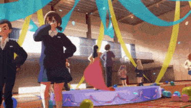 a group of people are standing in a gym with balloons and ribbons .