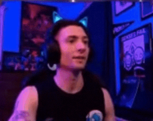 a man wearing headphones and a cat ear headband is standing in front of a blue wall .