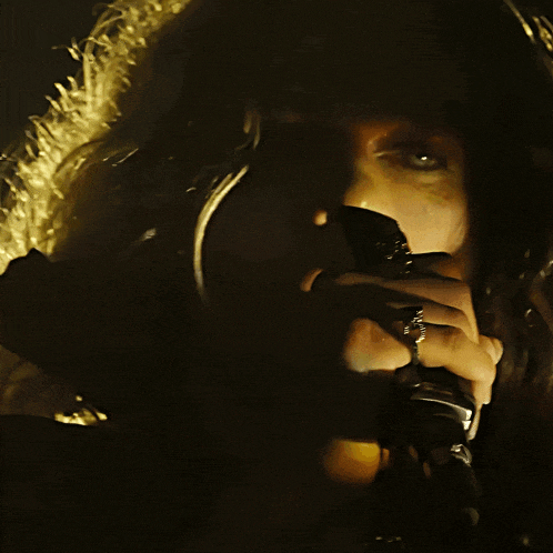 a woman with a ring on her finger is singing into a microphone in the dark
