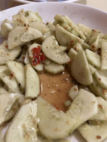a white plate topped with sliced cucumbers and a red pepper