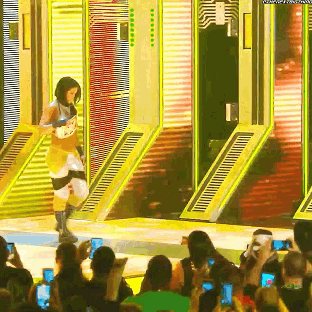a female wrestler is walking on a stage in front of a crowd while holding a sword .
