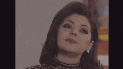 a close up of a woman 's face wearing earrings and a turtleneck sweater .