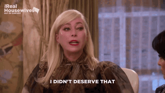 a woman says i did n't deserve that in front of a real housewives poster