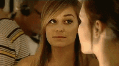 a woman is whispering into another woman 's ear while another woman looks on .