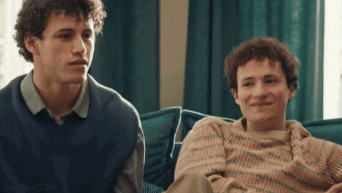 two young men are sitting next to each other on a couch and one of them has the word dna on his chest