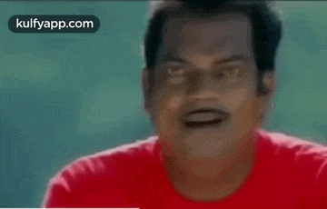 a man in a red shirt is making a funny face with his mouth open .