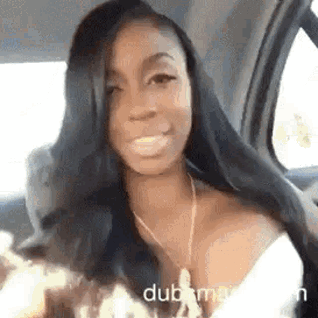 a woman with long black hair is sitting in the back seat of a car and smiling .
