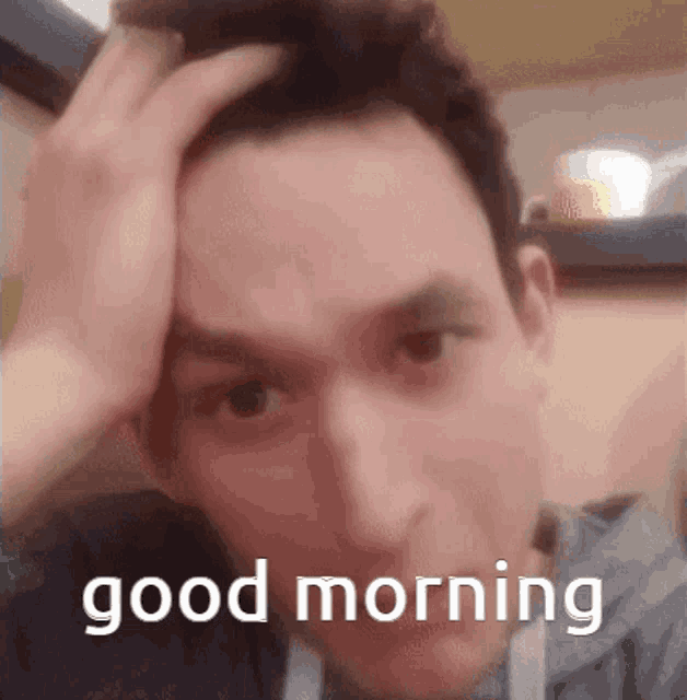 a man holds his hand to his forehead and says good morning .
