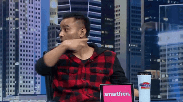 a man sitting at a desk with a tablet that says smartfren on it