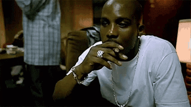 a man with a ring on his finger is smoking a cigarette while wearing a white shirt .