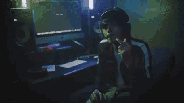 a man is sitting in front of a computer in a dark room with a clock on the wall .