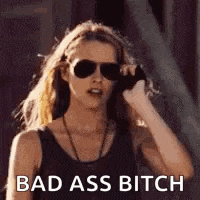 a woman wearing sunglasses is talking on a cell phone and says `` bad ass bitch '' .