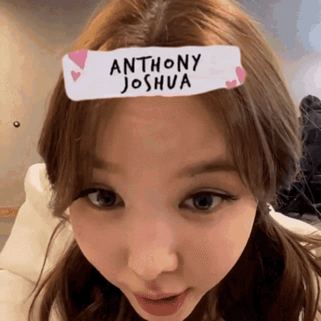 a close up of a woman 's face with a sticker on her forehead that says anthony joshua