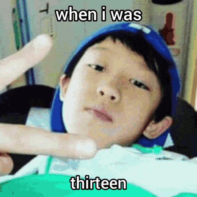 a young boy wearing a blue hat is making a funny face with the words when i was thirteen above him