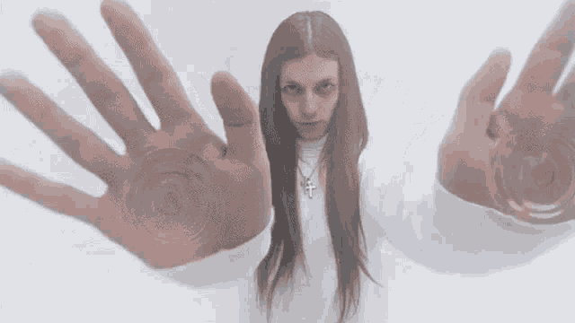 a woman in a white sweater is holding her hands out in front of a white background .