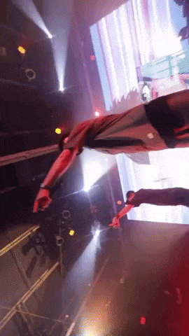 a man is flying through the air on a stage in front of a large screen