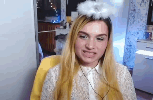 a woman wearing a headband with feathers on it is sitting in a chair .