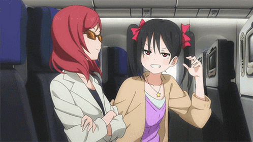 two anime girls are sitting on a plane and one is giving a peace sign