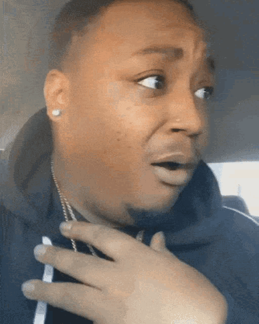 a man with a surprised look on his face wearing a black hoodie