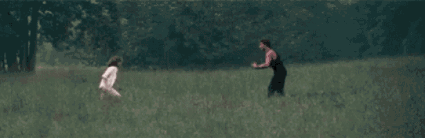 a man is carrying a woman on his shoulders in a field .