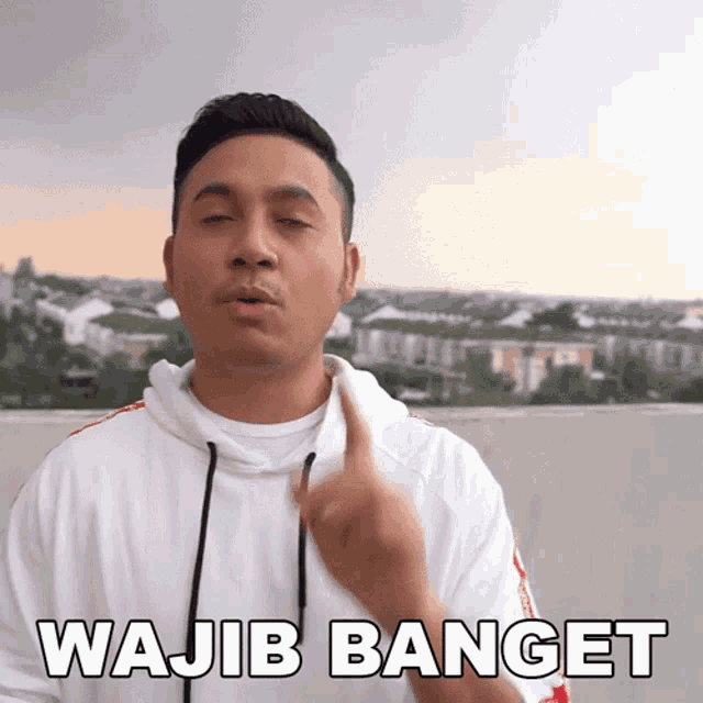 a man in a white hoodie says " wajib banget " with his eyes closed