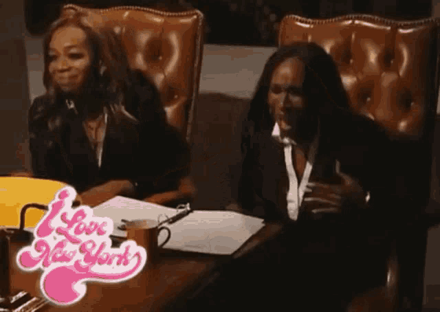two women sit at a table with a love new york logo