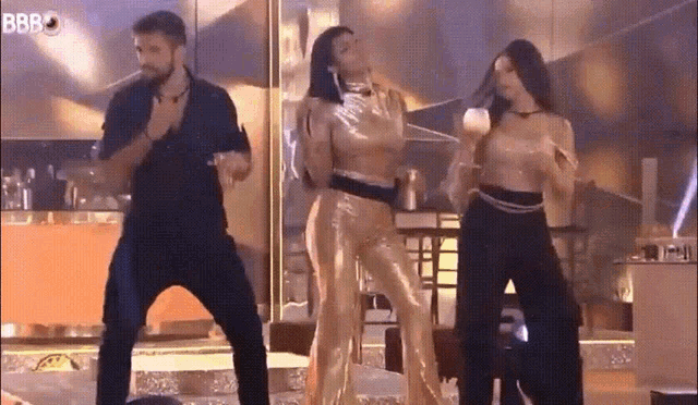 a man and two women are dancing on a stage in front of a sign that says bbbo .
