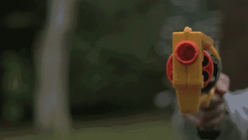 a person is holding a yellow toy gun with a red barrel
