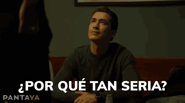 a man sitting on a couch with the words " por que tan seria " written on the bottom