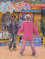 a man in a pink sweater and a man in a purple jacket are dancing in front of a building .