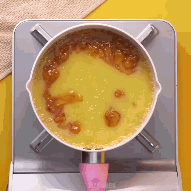 a pot of yellow liquid is on a stove with a pink handle that says incakes