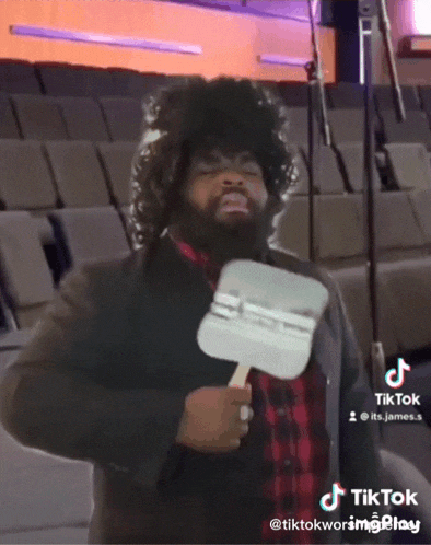 a man with a beard is holding a fan in his hand and a tiktok sticker on the bottom right