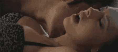 a man and a woman are laying down and kissing . the woman is wearing a leopard print bra .