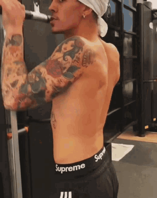 a shirtless man wearing supreme underwear is doing exercises