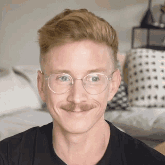 a man wearing glasses and a mustache is smiling
