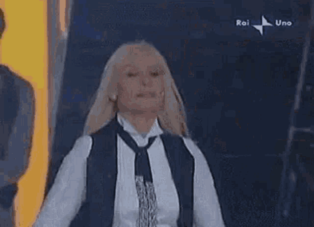 a woman in a white shirt and tie is dancing on a stage .