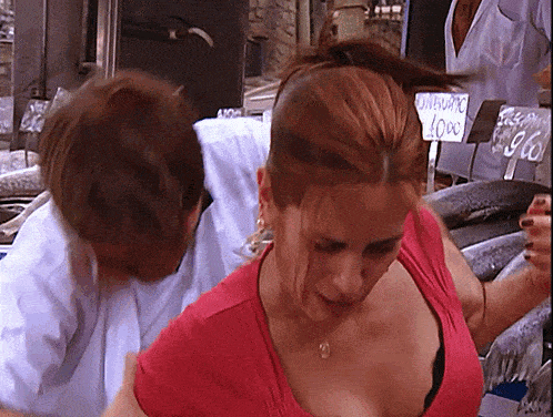 a woman in a red shirt is being held by a man in front of a sign that says gamberetti