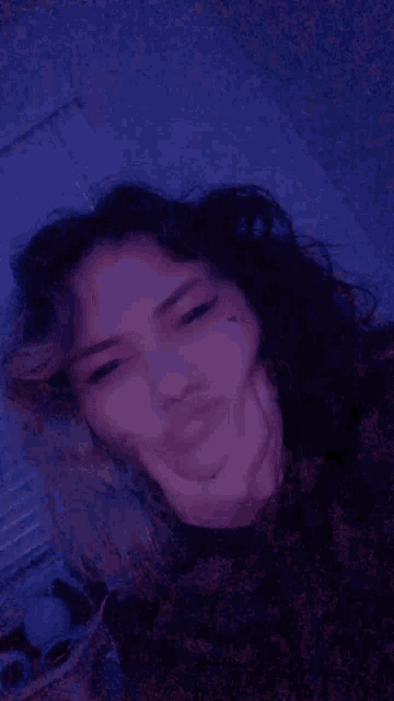 a woman is laying on a bed with her hand on her face and making a funny face .