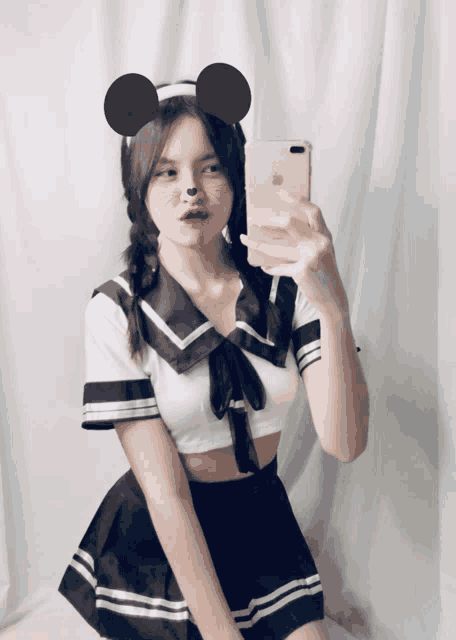 a girl wearing mickey mouse ears takes a selfie on her phone