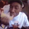 a man in a white shirt is eating a hamburger and drinking a beer .