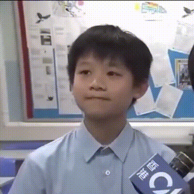 a young boy wearing a blue shirt is holding a microphone with the letter c on it .