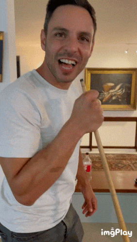 a man in a white shirt is holding a pool cue in front of a painting