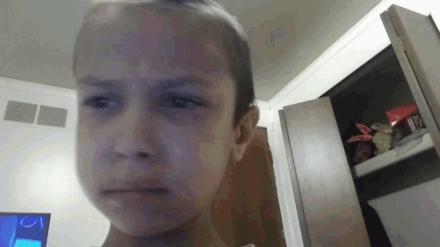 a young girl making a funny face in front of a closet with a box of m&m 's in it