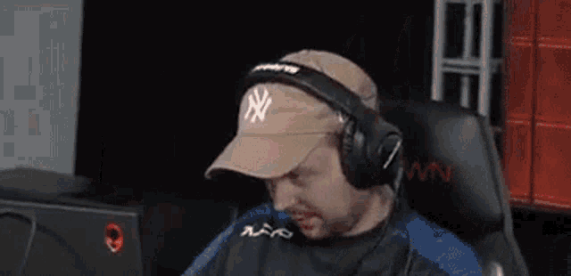 a man is sitting in a chair wearing headphones and a hat .