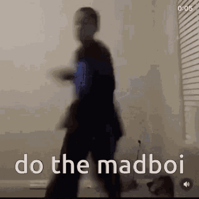 a blurry picture of a man walking in a room with the words `` do the madboi '' written on the bottom .