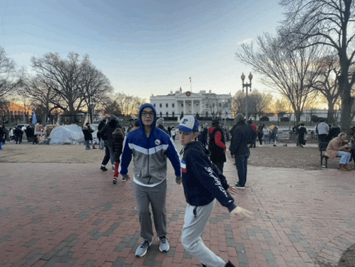two people walking in front of the white house with one wearing a hat that says ' washington redskins ' on it